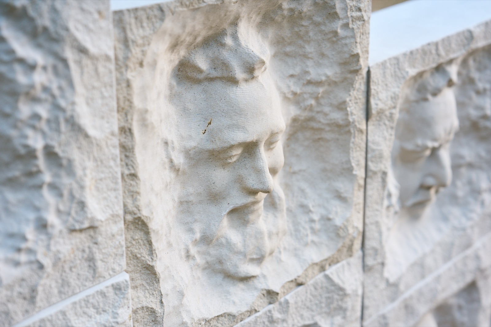 Close-up of a bearded face carved in relief into a limestone block.