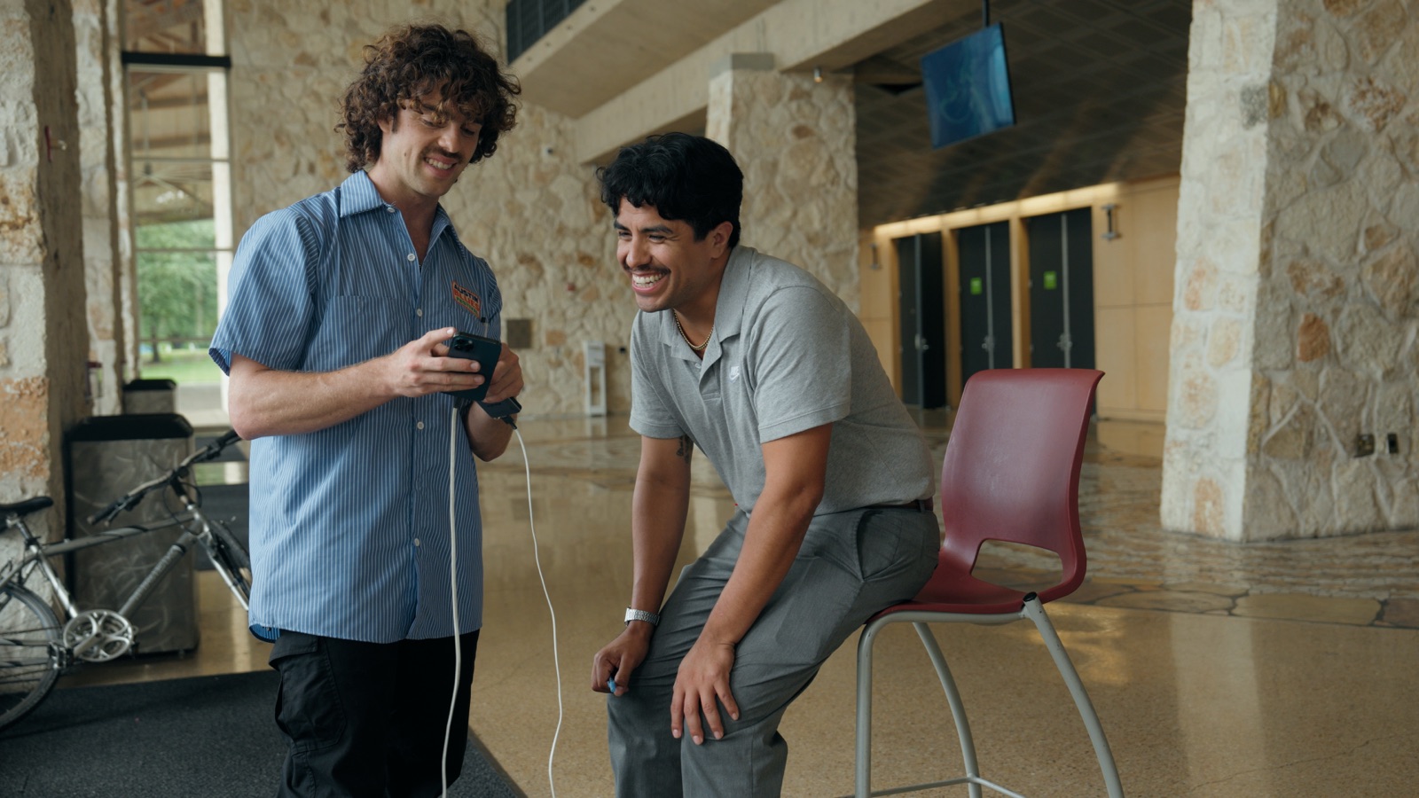 Two people laughing while reviewing a portrait scan on a phone inside the convention center.